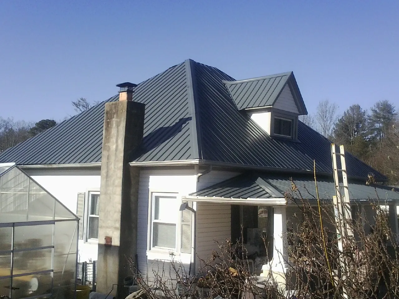 Dark blue standing seam metal roof on a white farmhouse with dormer — Slate & Tile Roof Repair by Roofing Brothers in Minersville