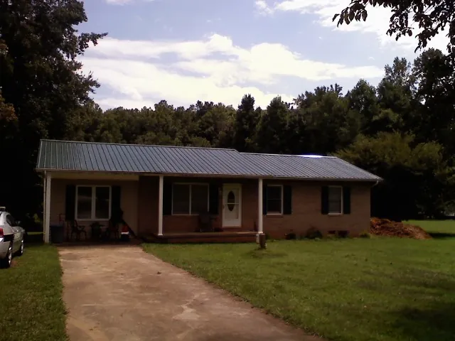 Dark green metal roof on a brick ranch with a covered porch in Minersville