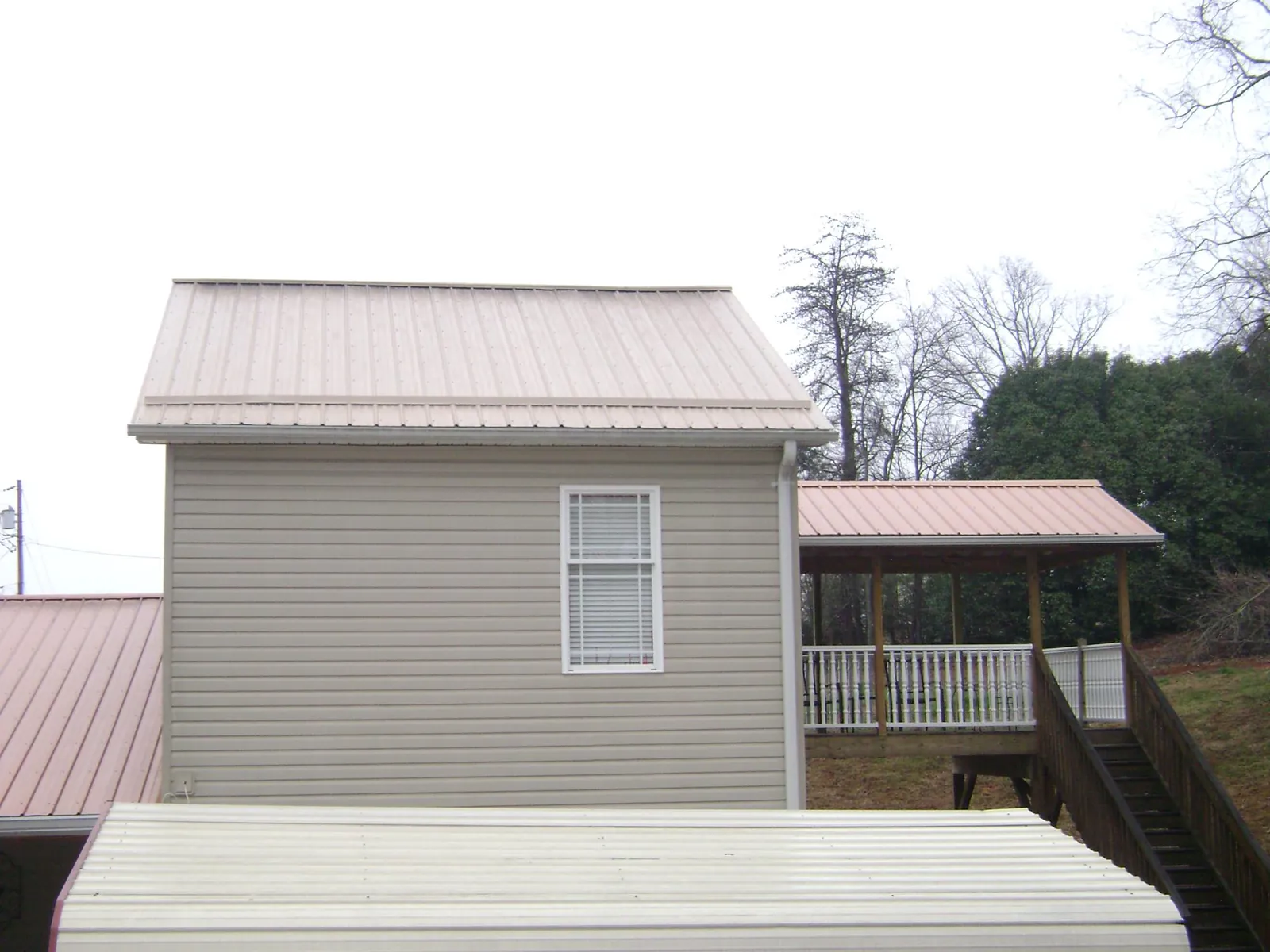 Tan metal roofs on a two story addition and attached porch, from a Roof Replacement job in Minersville
